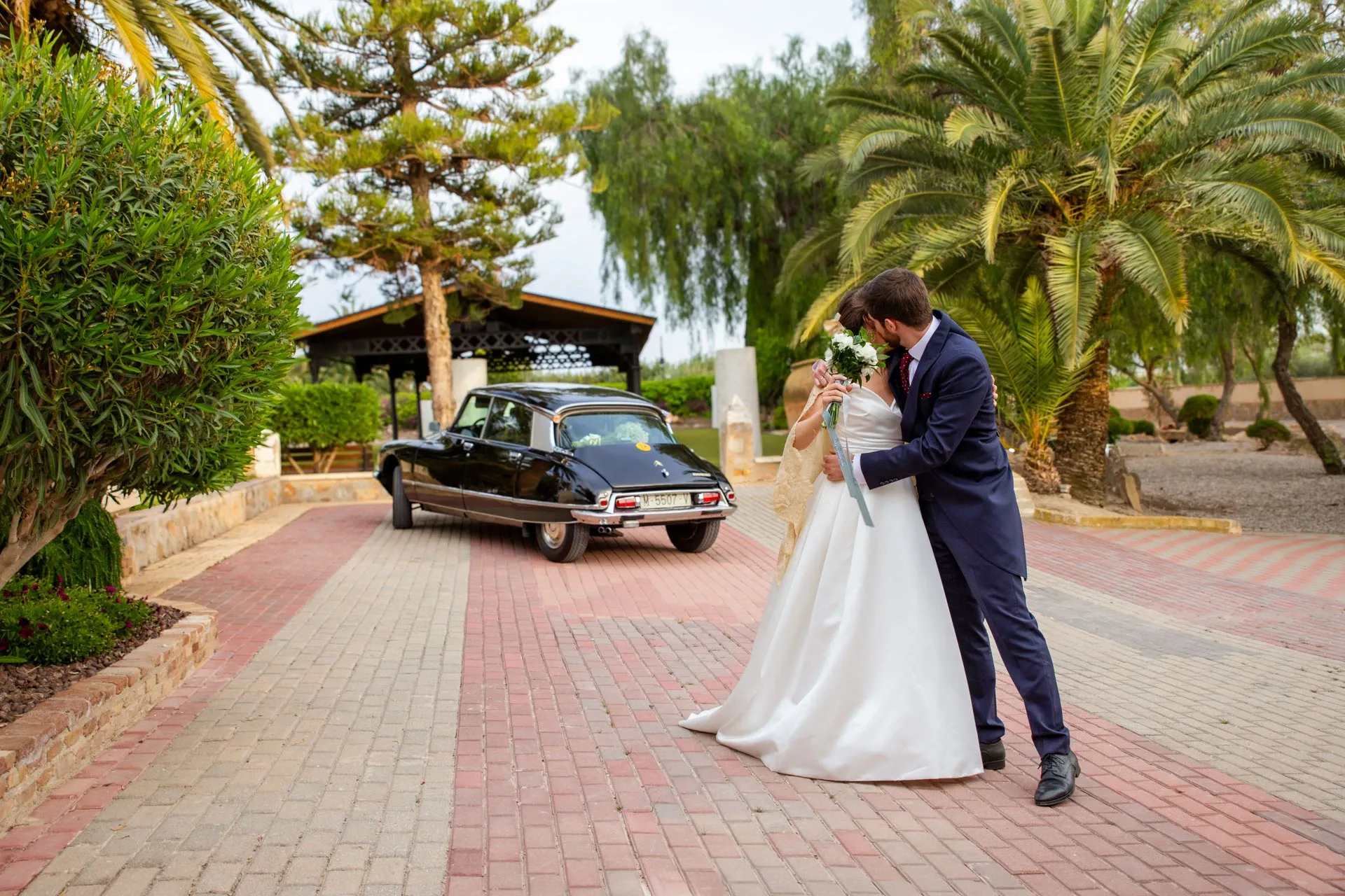 Novios abrazados junto al coche clásico