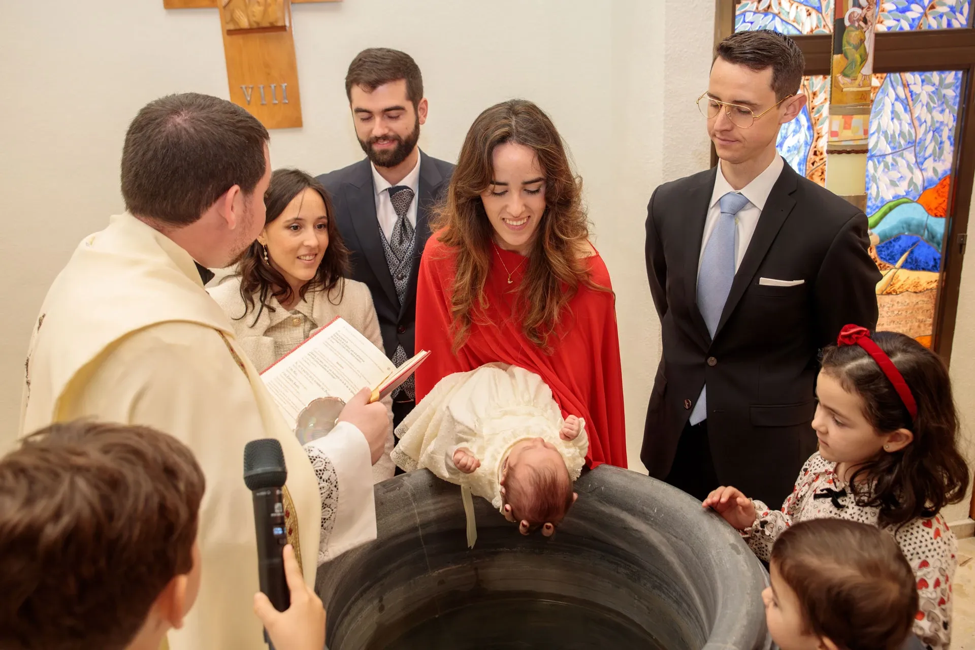 Sacerdote bautizando al bebé en la pila bautismal