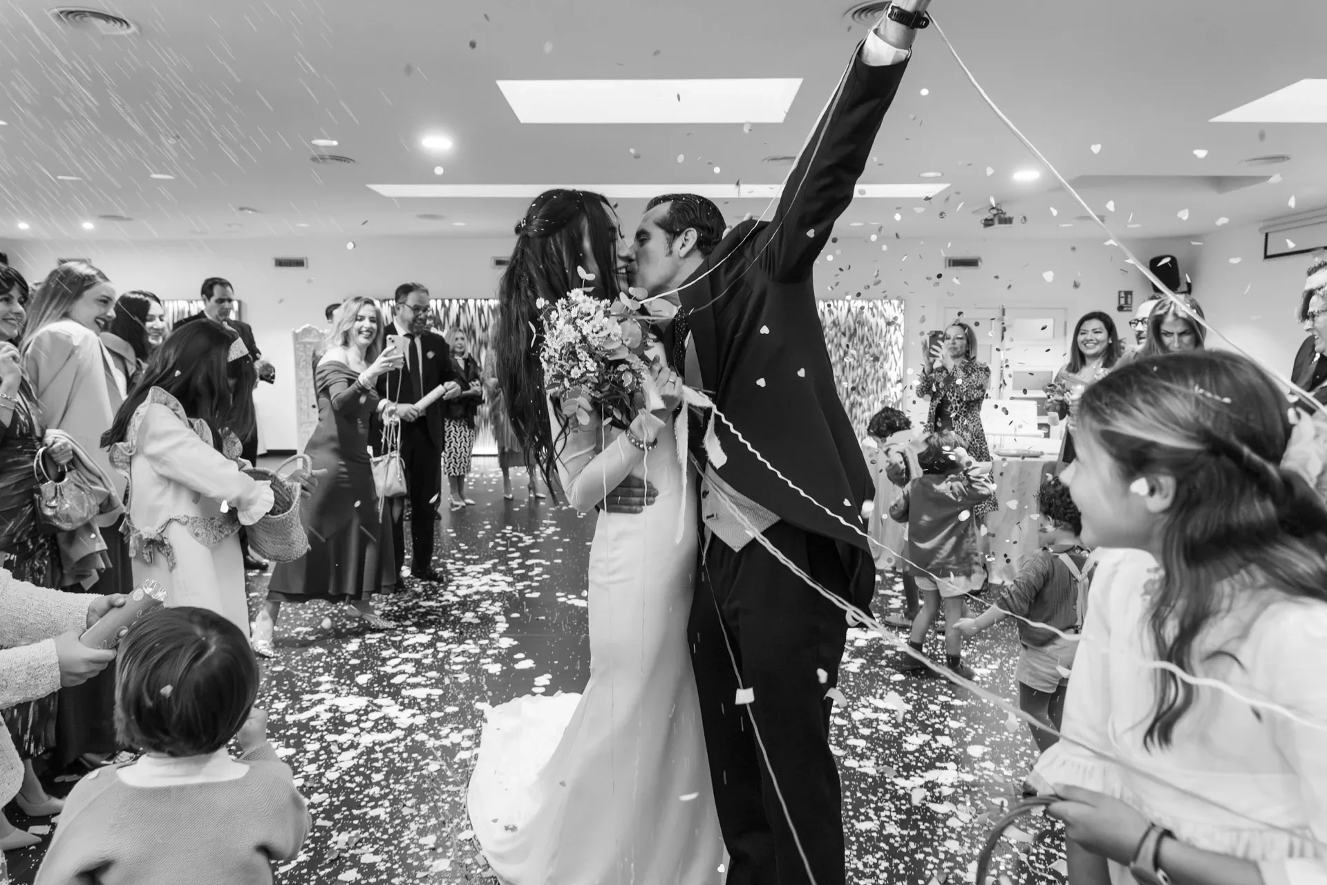 Novios celebrando entre confeti, en blanco y negro