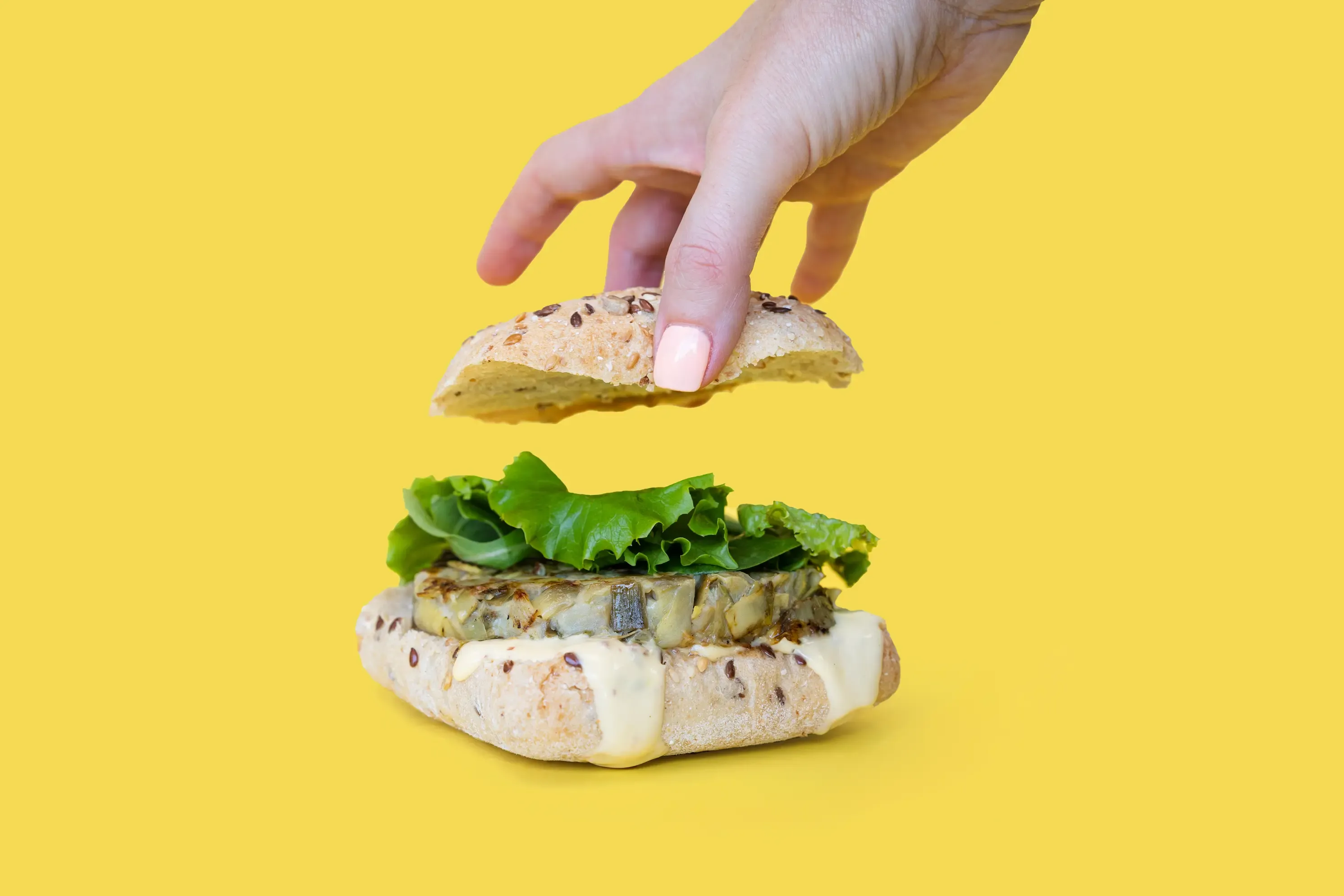 Mano levantando la tapa de un sándwich