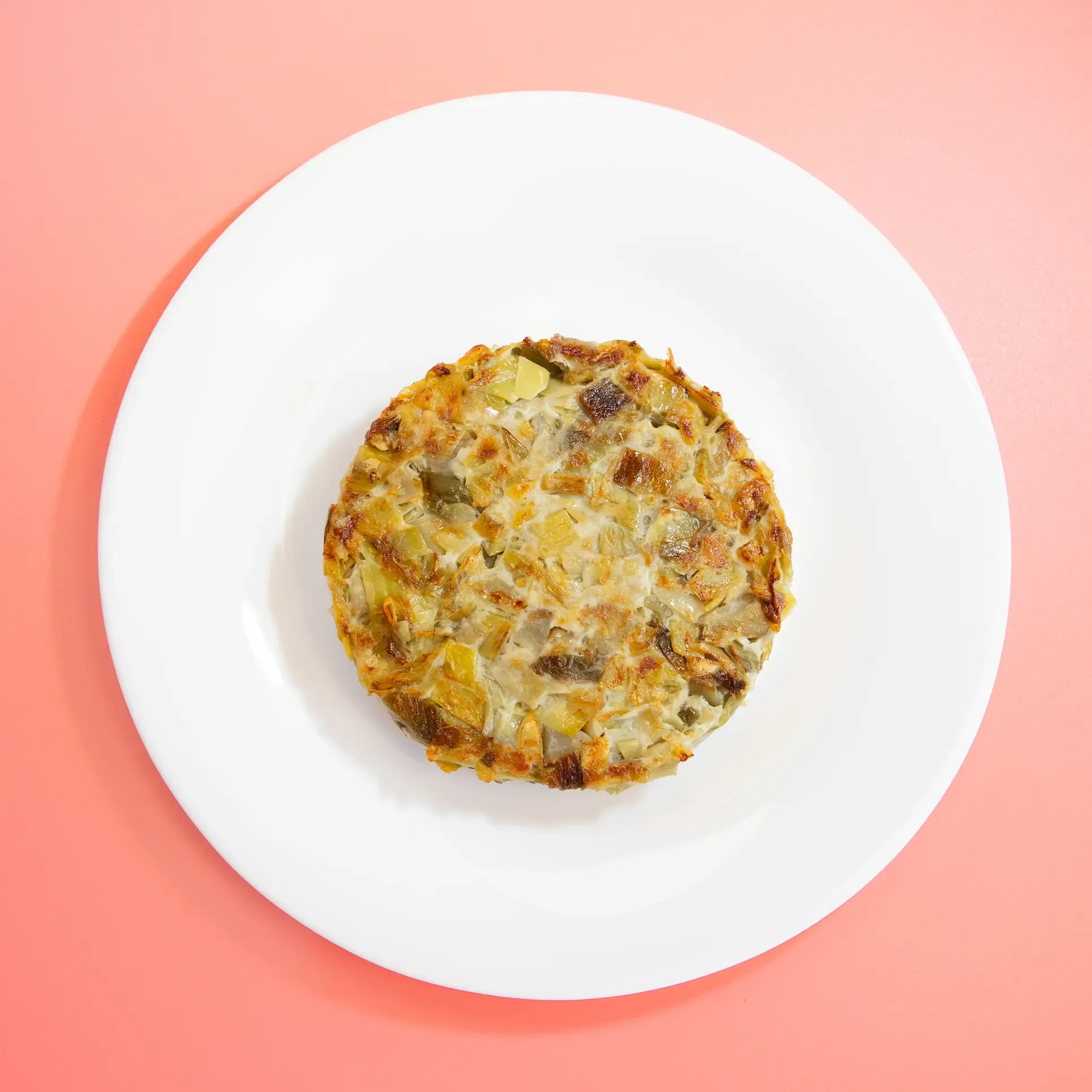 Tortilla en un plato sobre fondo rosa