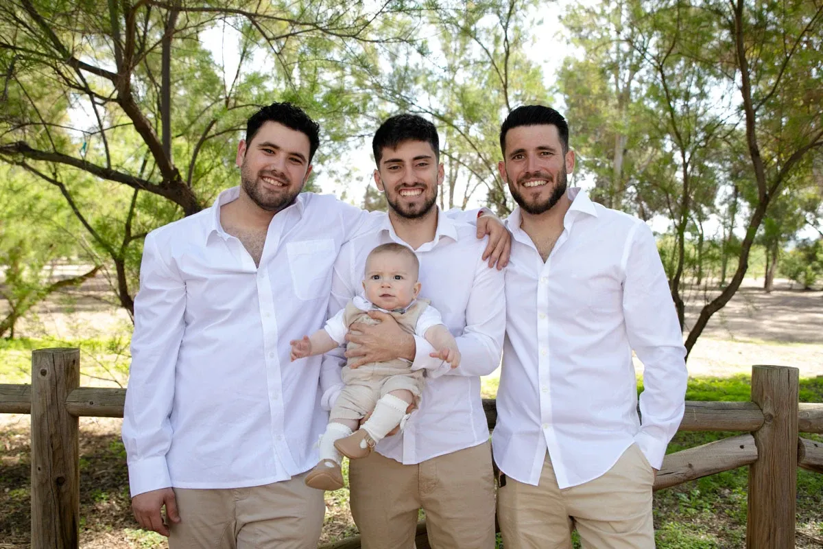 Familia con el bebé en una sesión al aire libre junto a una valla