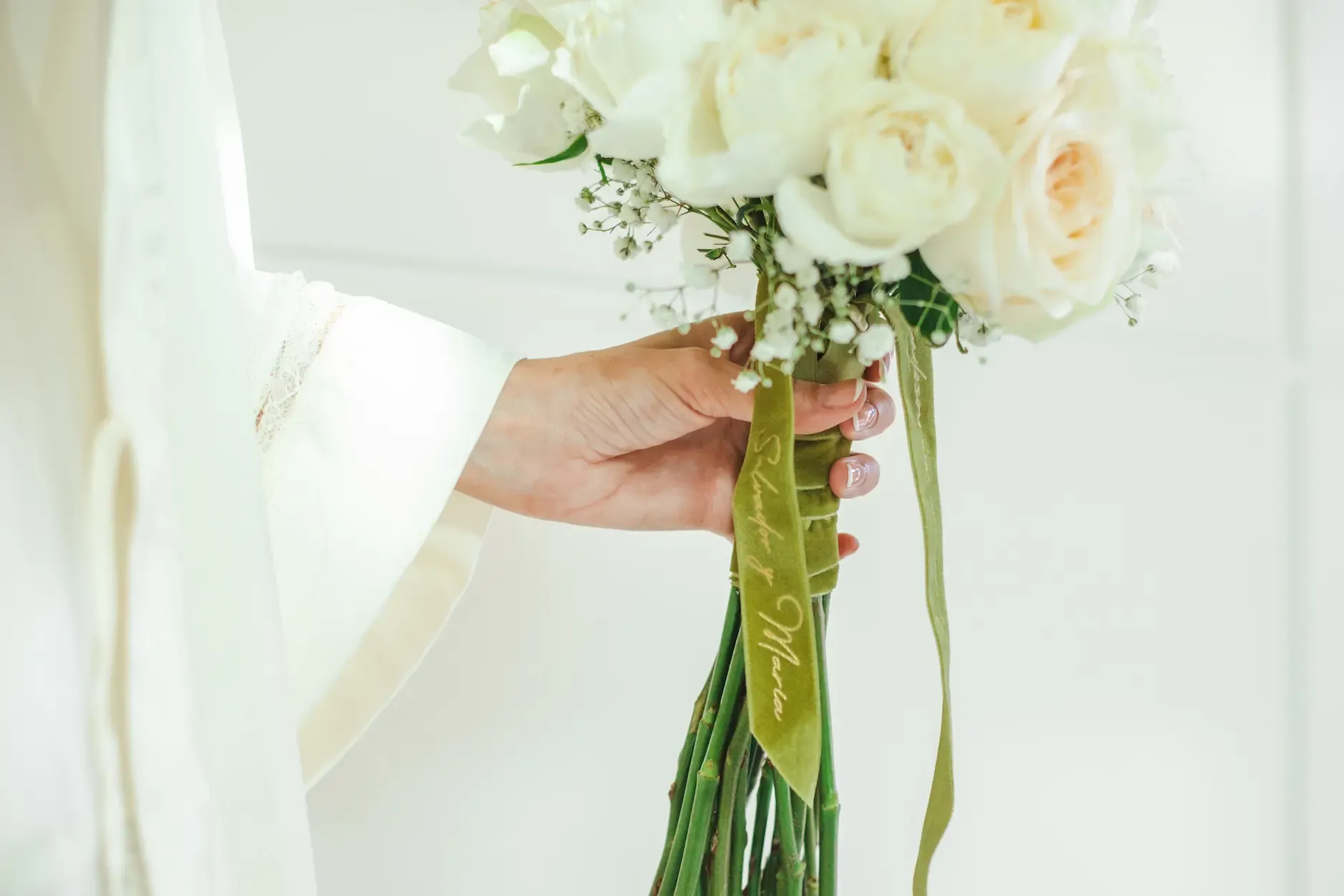 Novia sujetando su ramo de rosas blancas
