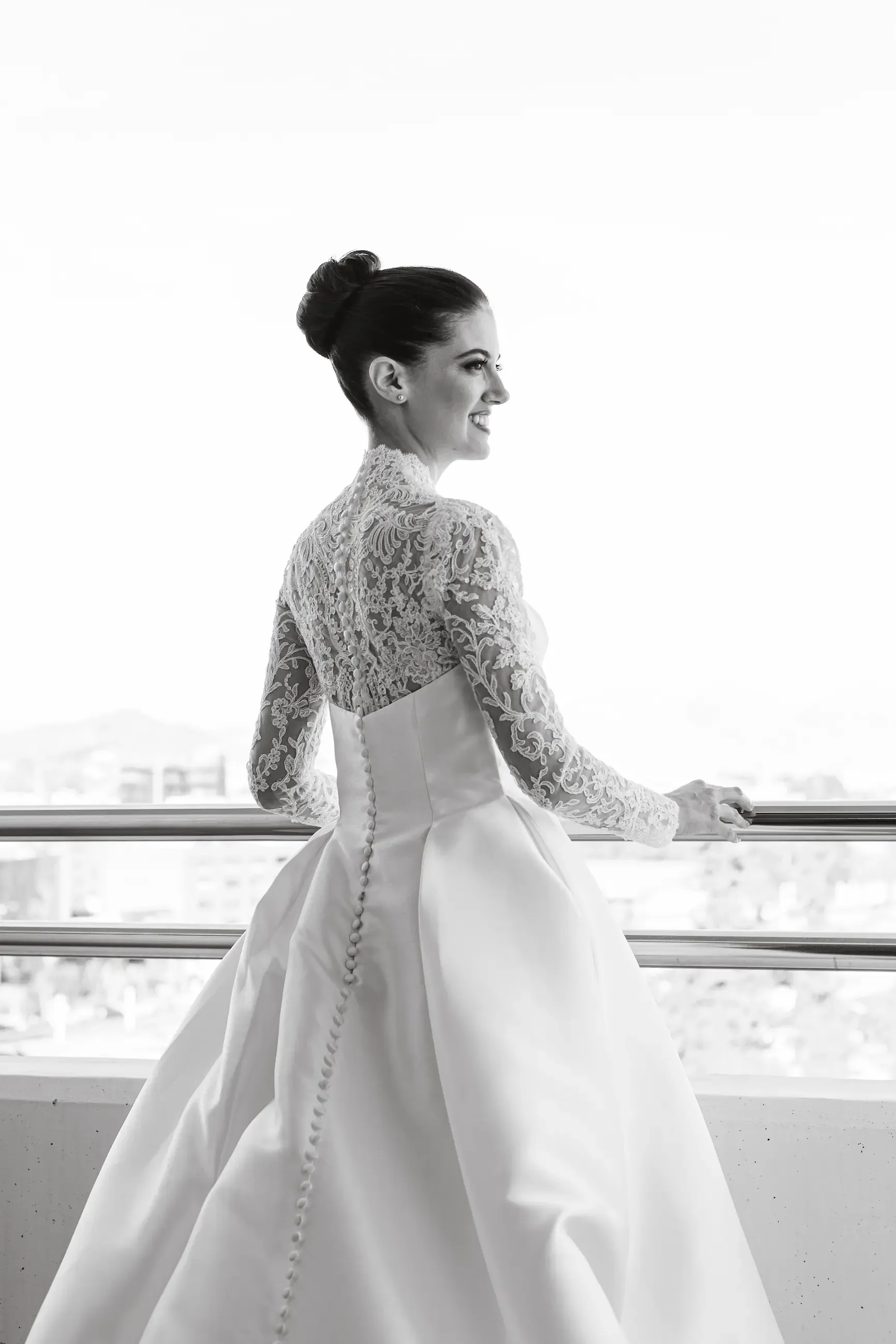 Novia con vestido de encaje junto a la ventana