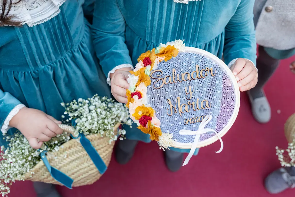 Cartel de boda con flores llevado por los niños de arras