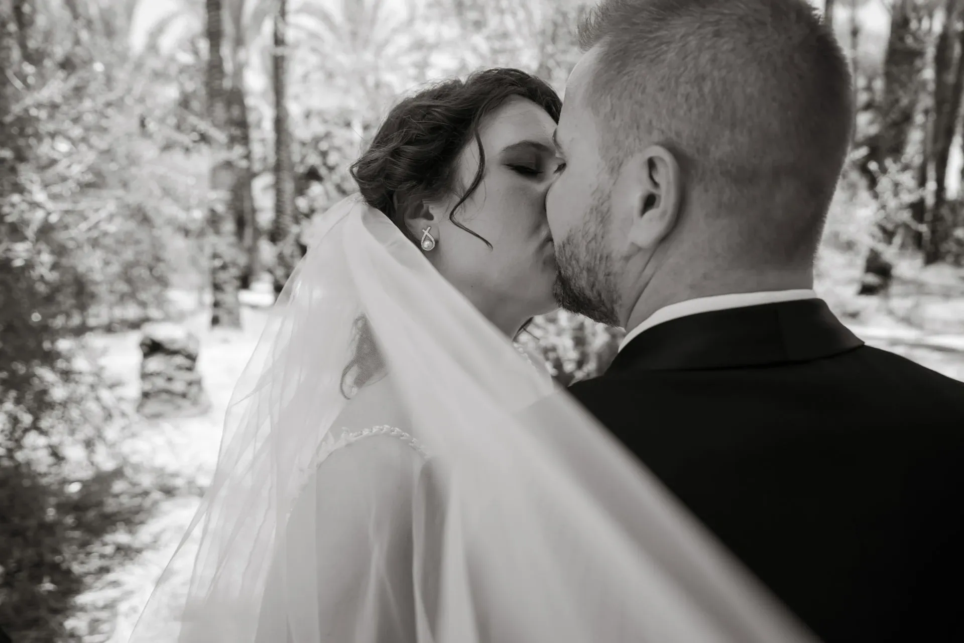 Beso de los novios con velo, en blanco y negro