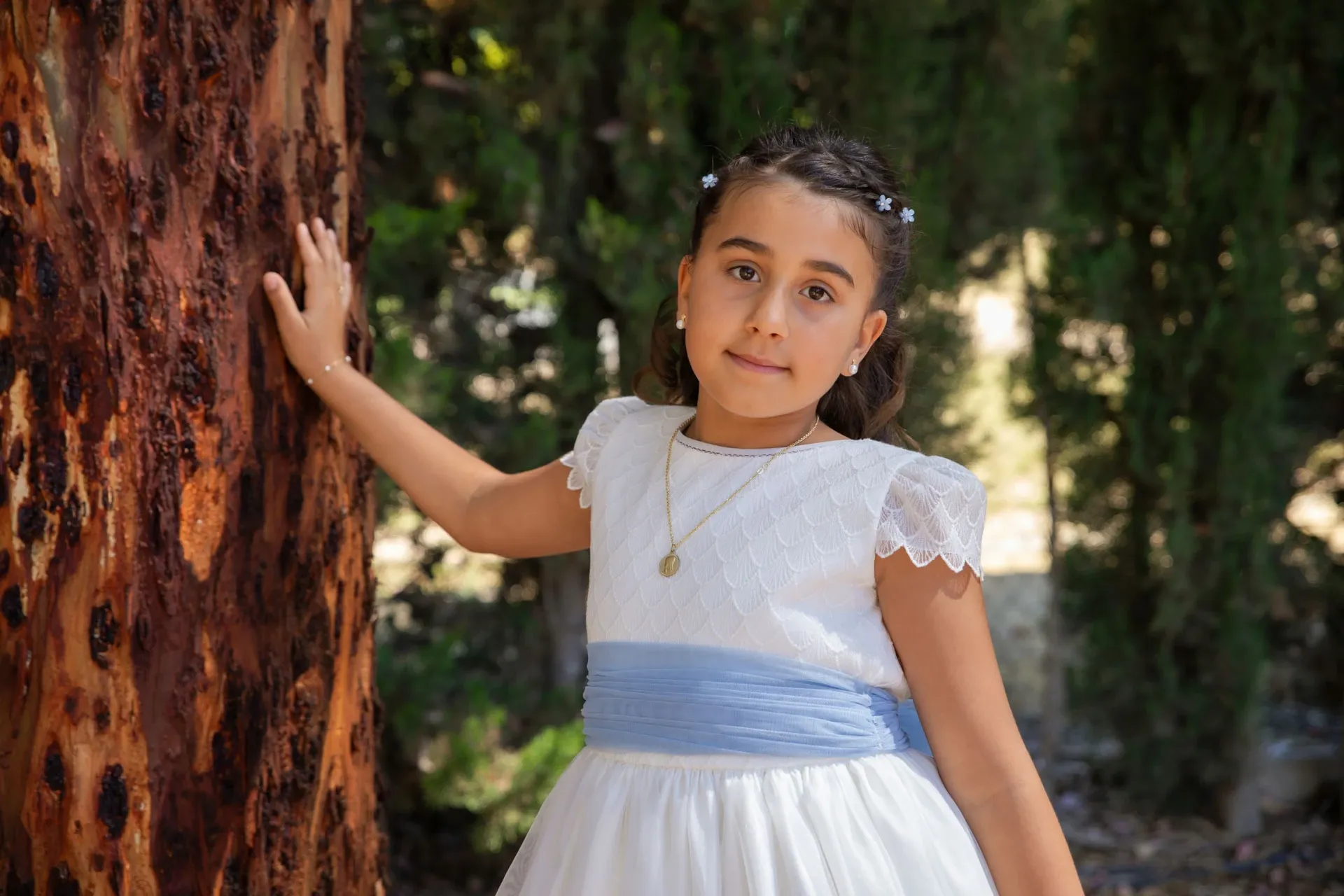 Niña de comunión junto a un árbol