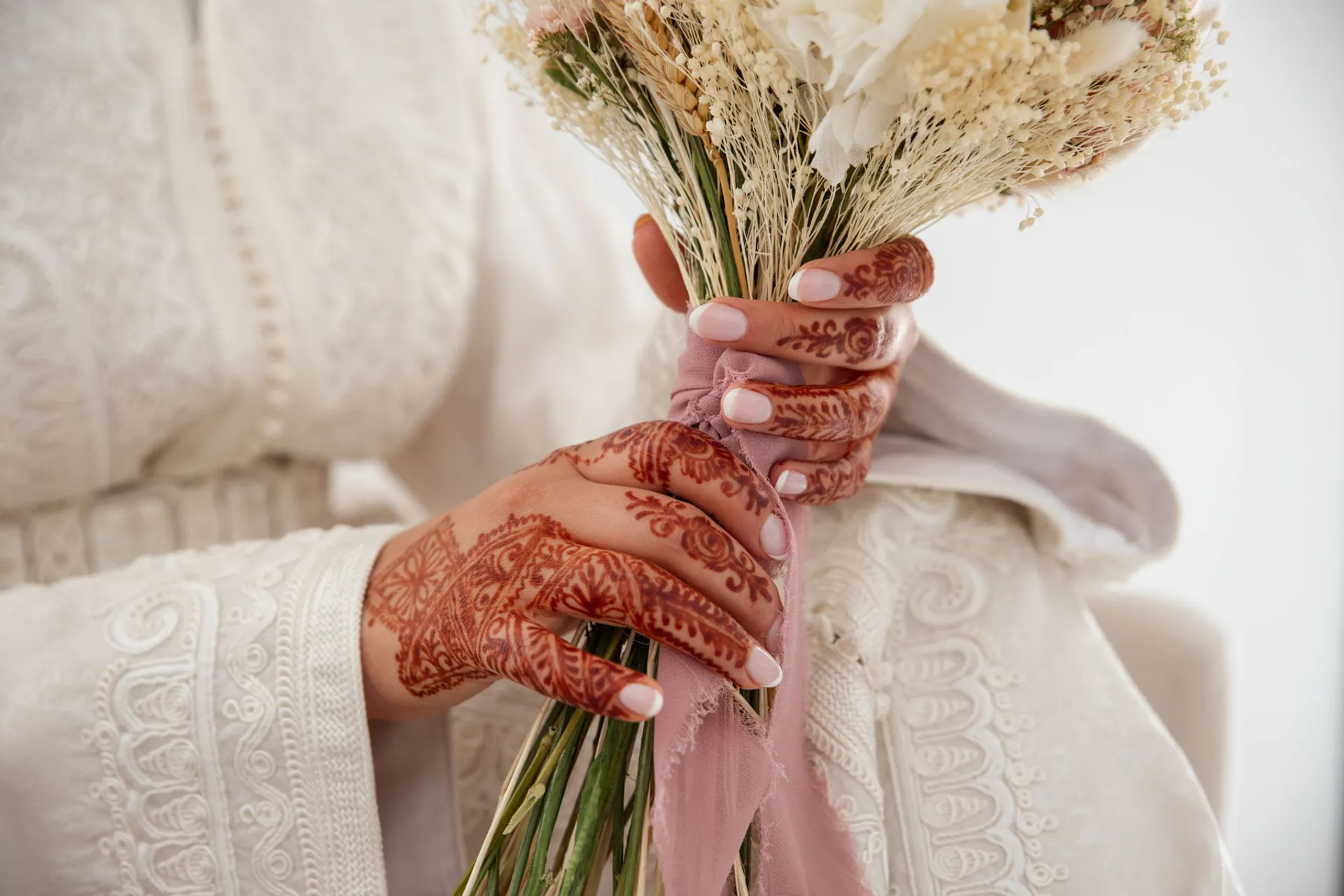 Manos de la novia con henna sujetando el ramo