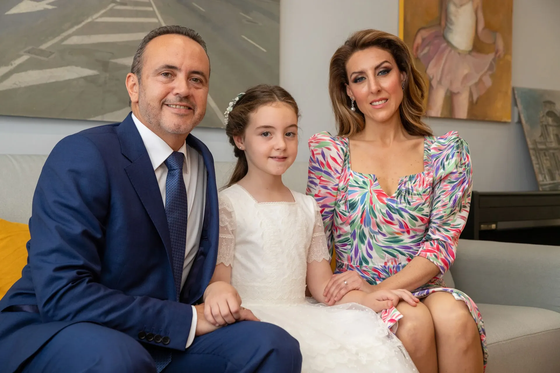 Niña de comunión con sus padres en casa
