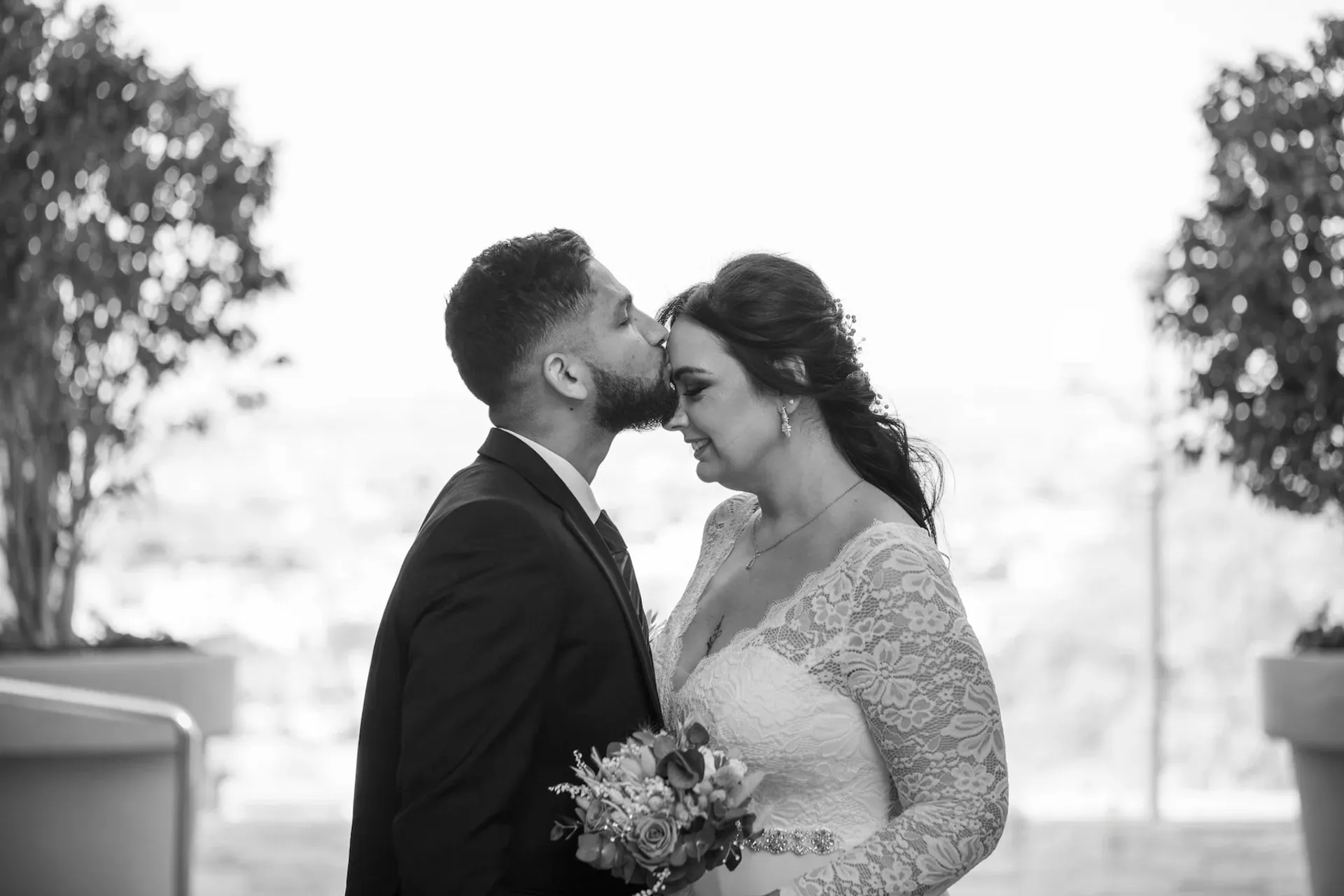 Novio besando la frente de la novia, en blanco y negro