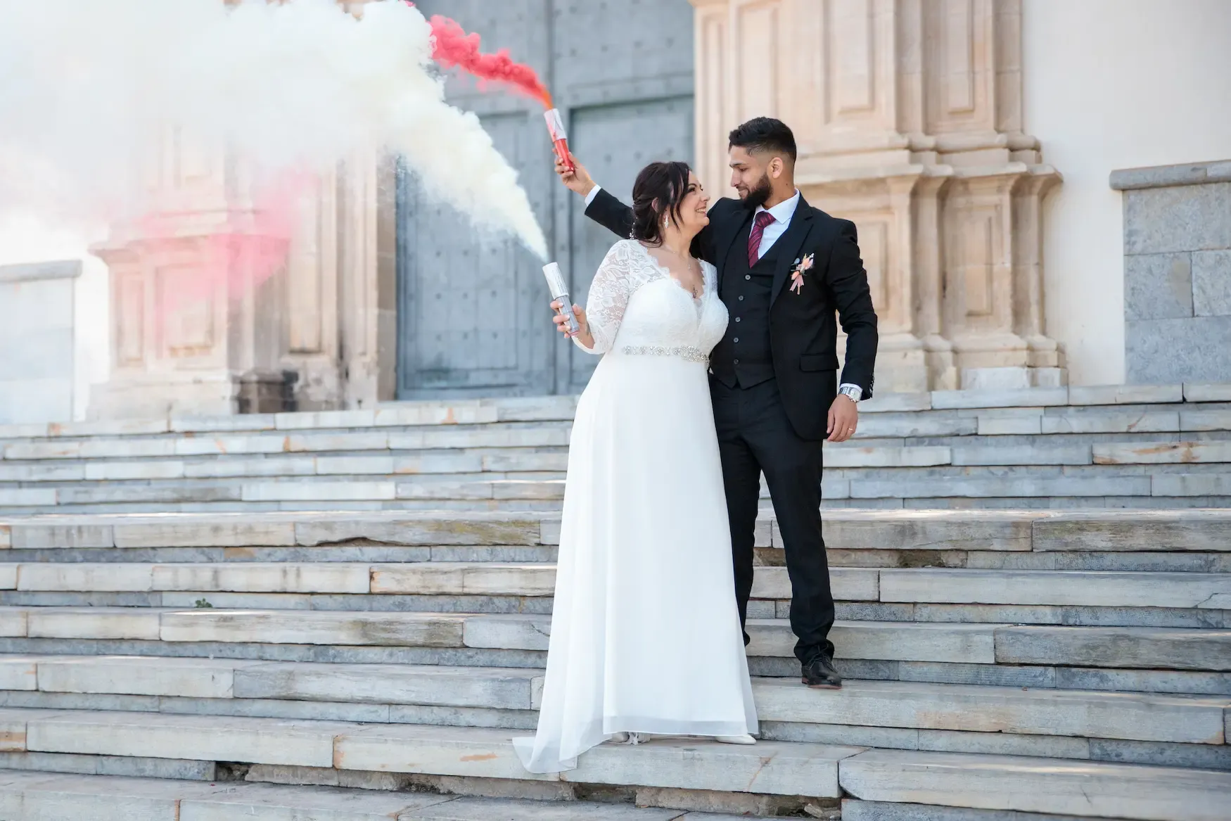 Novios con bengalas de humo en las escaleras de la iglesia
