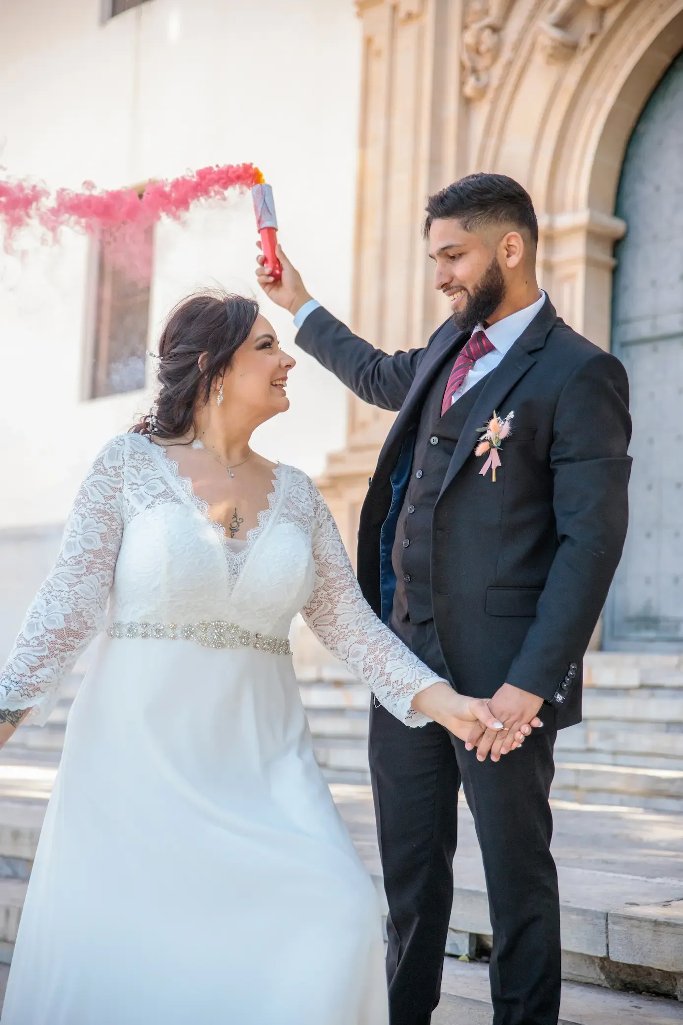 Novios con bengala de humo rosa frente a la iglesia