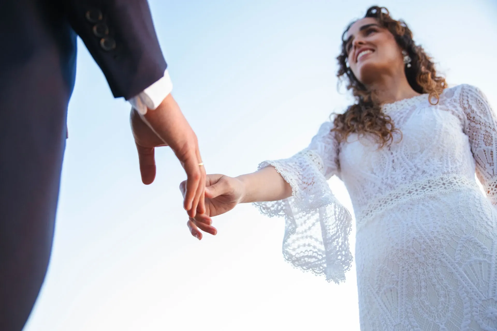 Novios cogidos de la mano contra el cielo