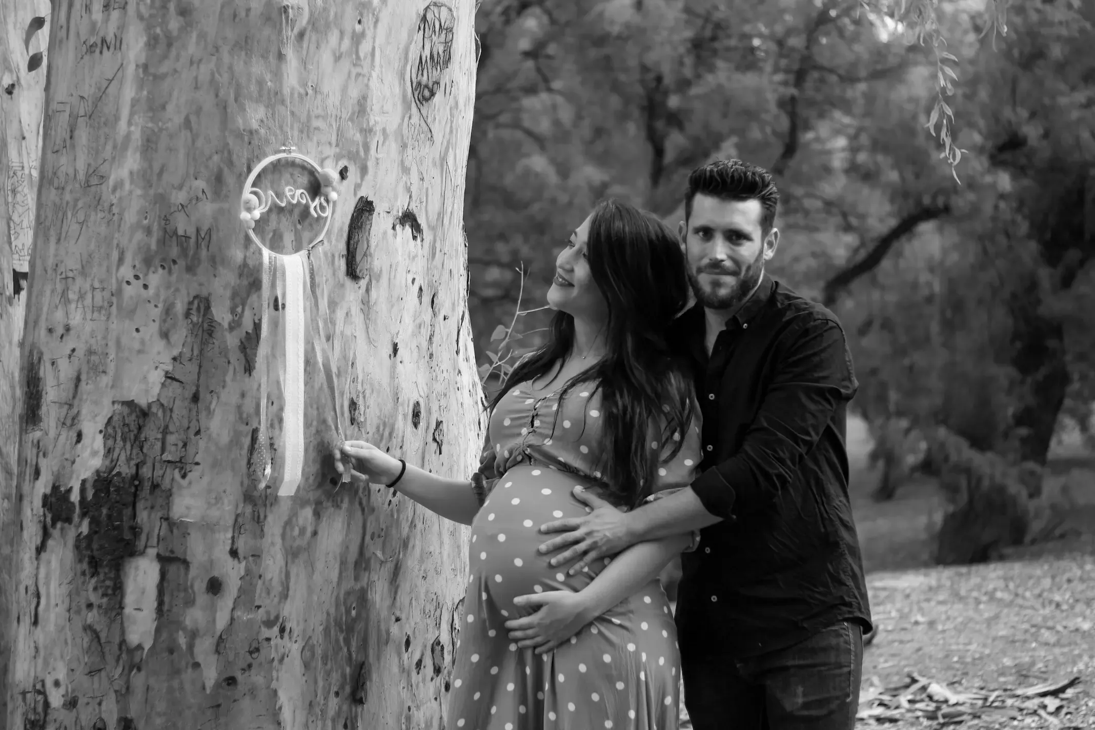 Futuros padres junto a un árbol, en blanco y negro
