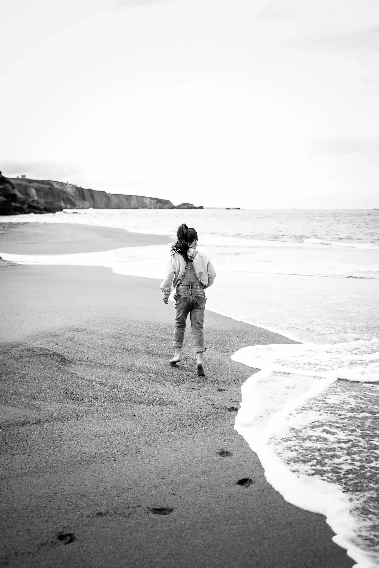 Madre e hija paseando por la playa, en blanco y negro
