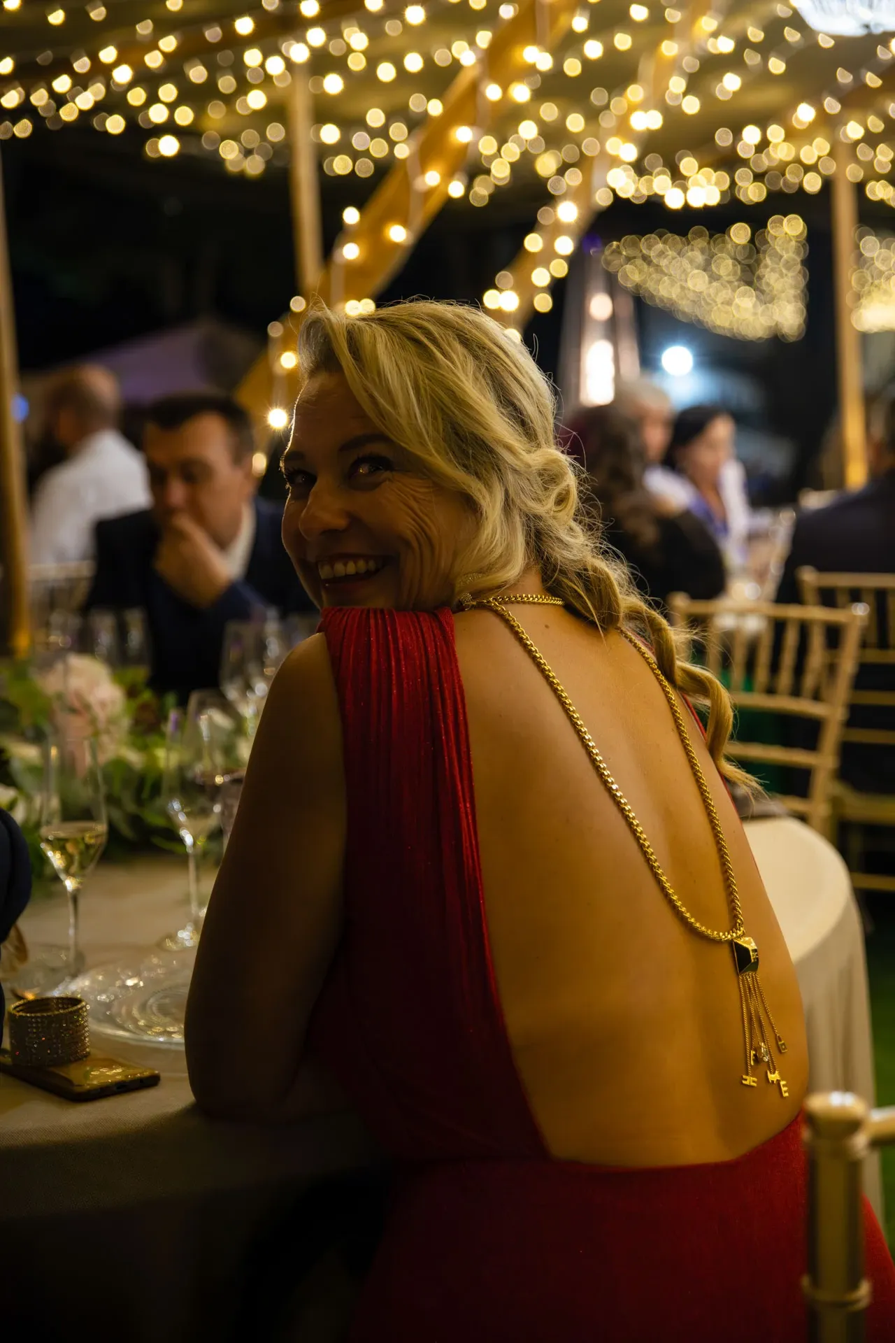 Invitada sonriendo en un banquete de boda nocturno