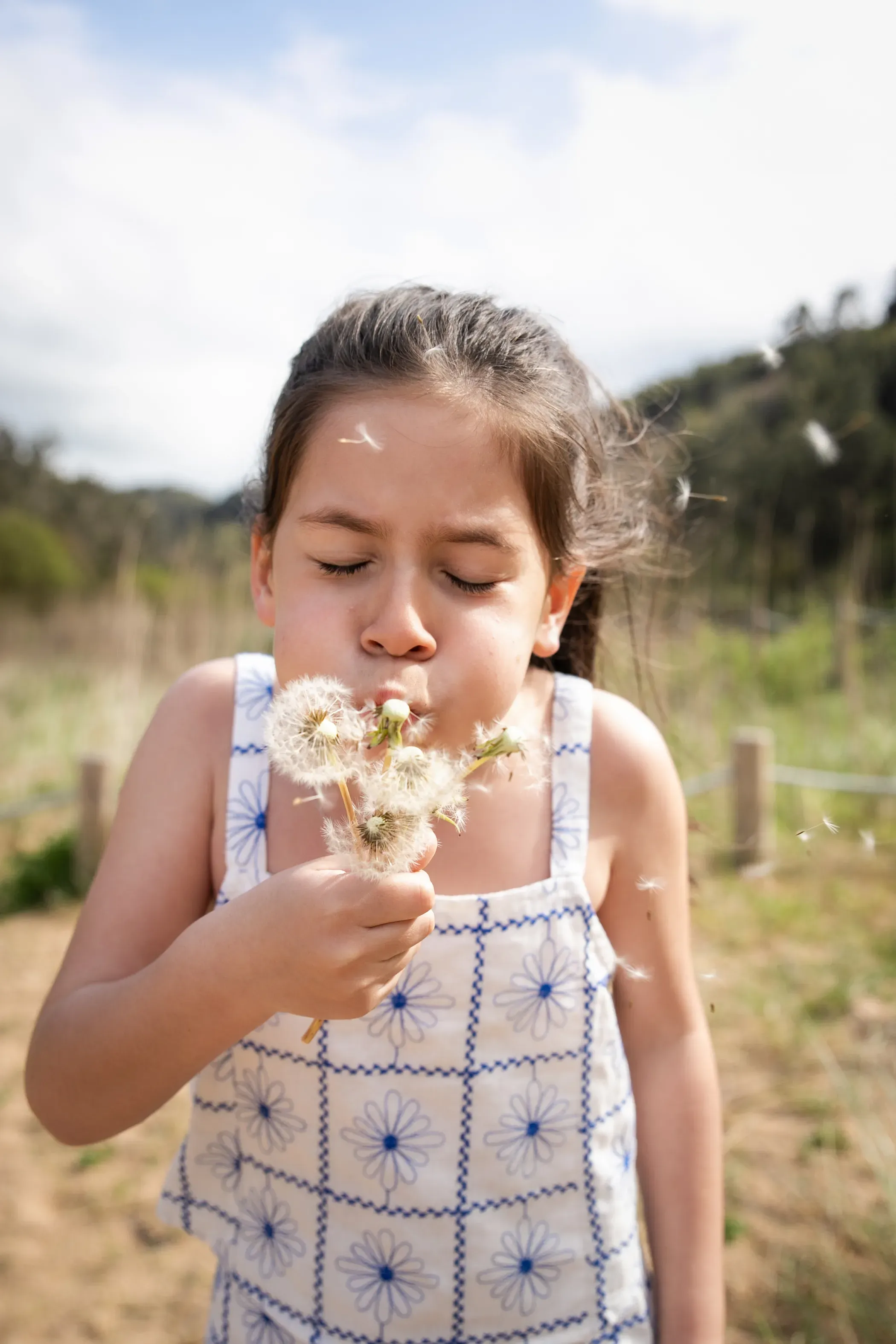 Niña soplando un diente de león