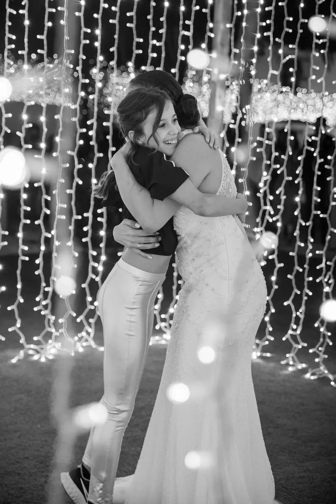 Novia abrazando a una amiga bajo las luces de la fiesta