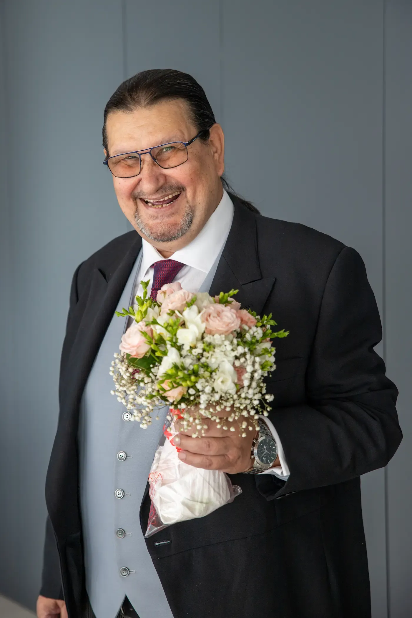 Padrino sonriente con el ramo de la novia