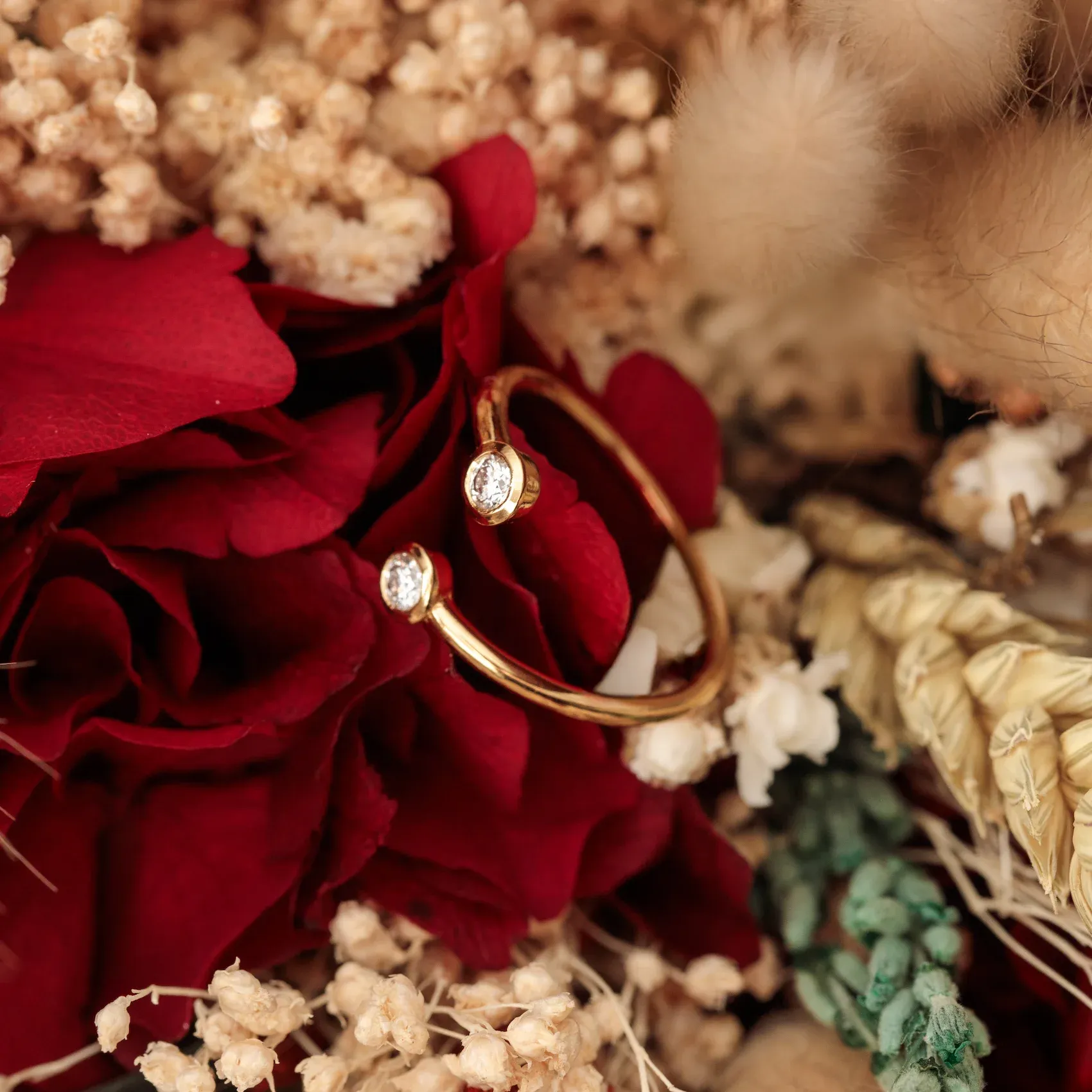 Anillo dorado con piedras sobre flores secas y rosas