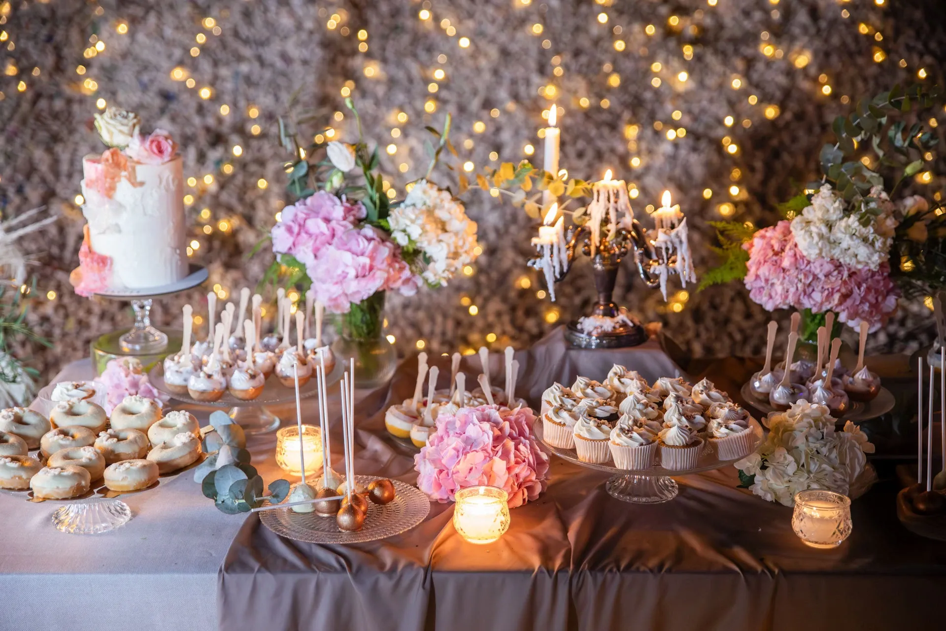 Mesa dulce con tartas, velas y flores en un banquete de boda