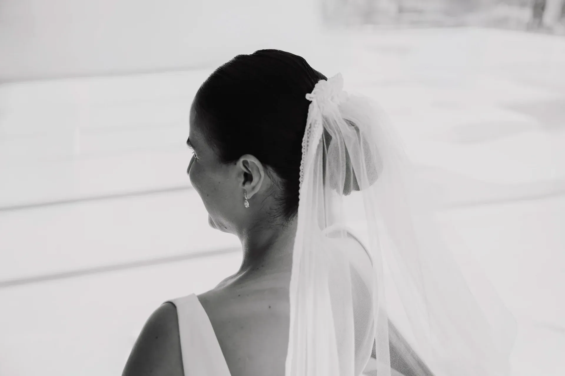Novia con velo mirando por la ventana, en blanco y negro