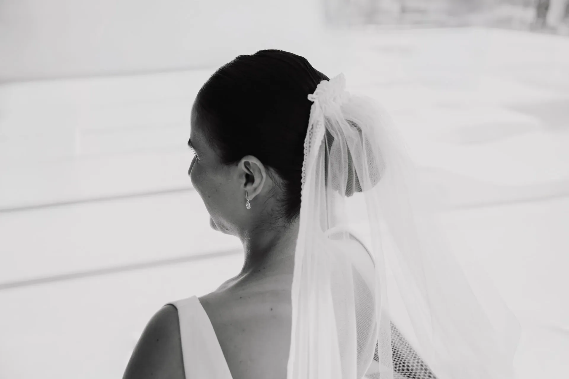 Novia con velo mirando por la ventana, en blanco y negro