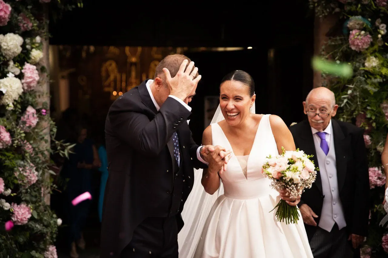Novia sonriente saliendo de la iglesia con el padrino
